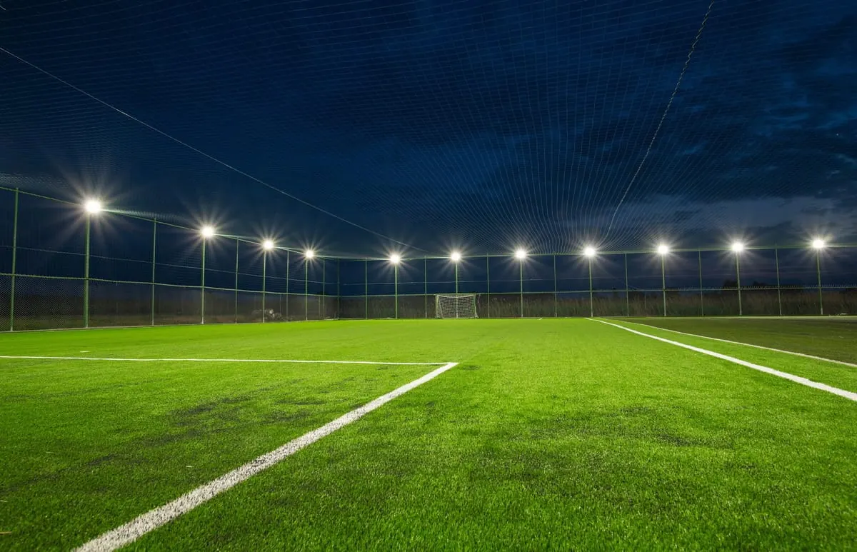 Greenfield Club football pitch under floodlights at sunset